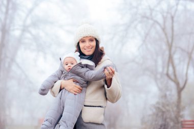 Anne, bebeği kışın yürüyüşe çıkarıyor. 