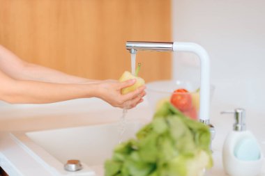 Mutfak lavabosunda sebze yıkayan kişi.