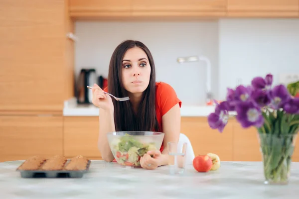 台所に一人でサラダを食べる女が食べ物に囲まれて — ストック写真