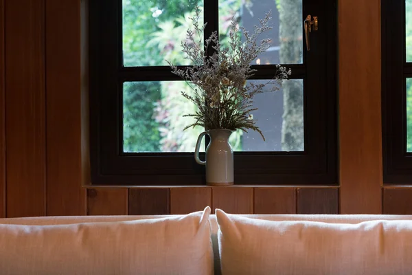 Travesseiro, sofá e flor ao lado da janela — Fotografia de Stock
