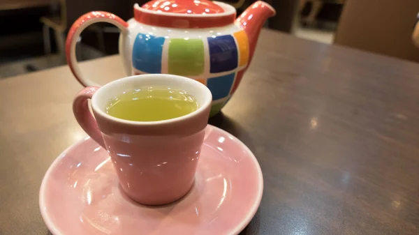 Heißer grüner Tee in rosa Tasse mit bunten Teekanne — Stockfoto