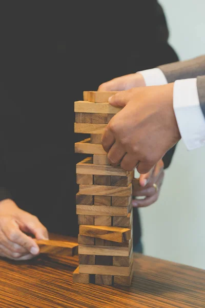 stock image businessman gambling placing wooden block on a tower - planning,