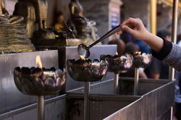 Persone versano olio per accendere candela in lanterna di olio a templ buddista — Foto Stock