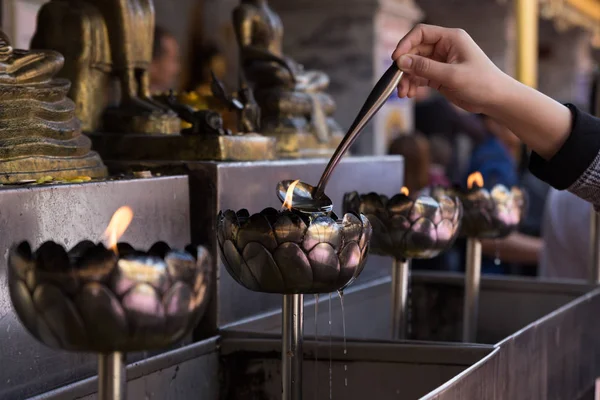 Persone versano olio per accendere candela in lanterna di olio a templ buddista — Foto Stock