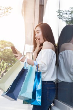 smartphone ve renkli alışveriş torbaları, mutlu Asyalı kadın 
