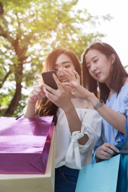 smartphone ve renkli alışveriş torbaları, mutlu Asyalı kadın 