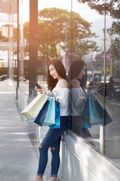 Gelukkig Aziatische vrouw met smartphone en kleurrijke tassen van de shopping bij — Stockfoto