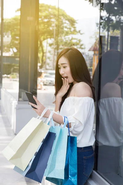 smartphone ve renkli alışveriş torbaları, mutlu Asyalı kadın 