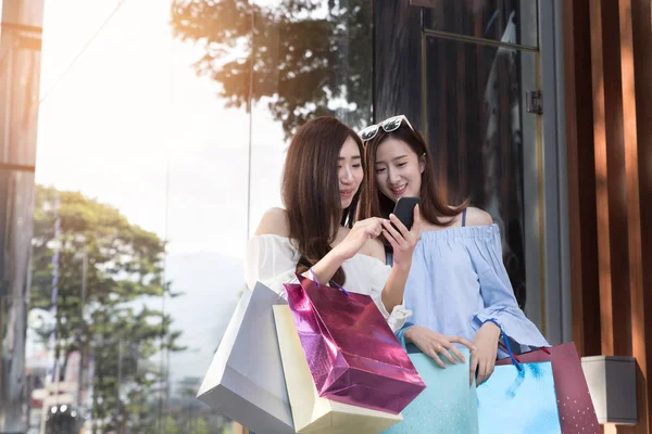 Mujer asiática feliz con teléfono inteligente y bolsas de compras de colores en — Foto de Stock