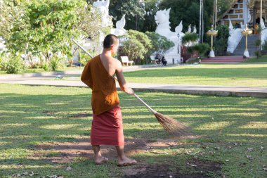 Budist rahip süpürge ile çalışma çim üzerinden düşen yapraklar temizleyicileri 