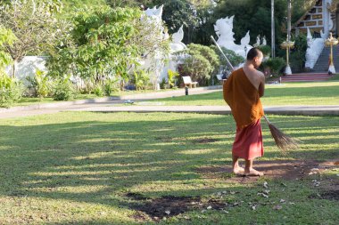 Budist rahip süpürge ile çalışma çim üzerinden düşen yapraklar temizleyicileri 