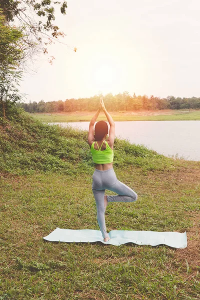 Junge Frau praktiziert Yoga-Übungen im Freien im Park, entspannen Sie sich in — Stockfoto