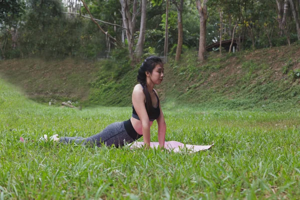 Mujer joven practicando ejercicios de yoga al aire libre en el parque, relajarse en — Foto de Stock