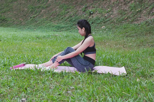 Wanita muda duduk di atas tikar setelah latihan di luar ruangan di taman, rel — Stok Foto