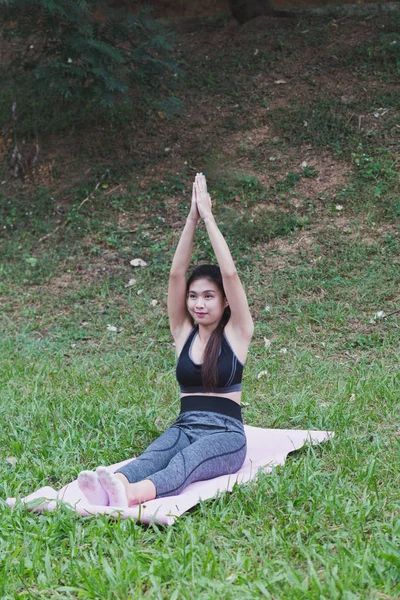 Mujer joven practicando ejercicios de yoga al aire libre en el parque, relajarse en — Foto de Stock