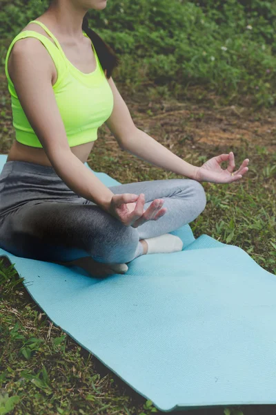 Junge Frau meditiert während sie Yoga im Freien im Park praktiziert, — Stockfoto