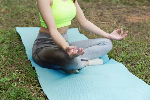 Junge Frau meditiert während sie Yoga im Freien im Park praktiziert, — Stockfoto