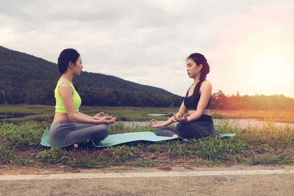 Junge Frau meditiert während sie Yoga im Freien im Park praktiziert, — Stockfoto