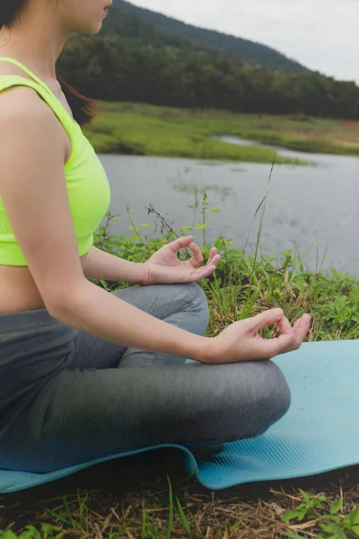Junge Frau meditiert während sie Yoga im Freien im Park praktiziert, — Stockfoto