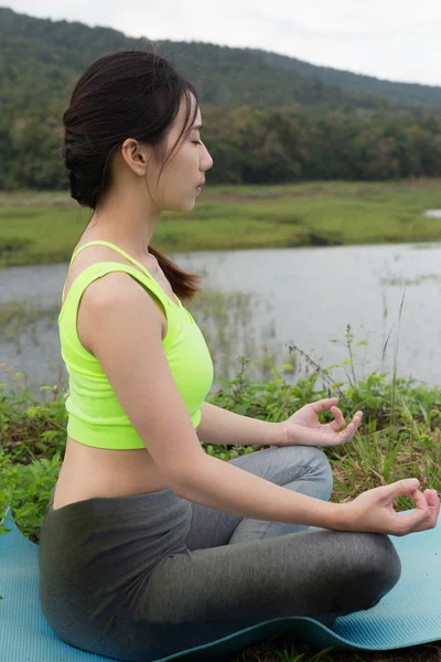 Joven medita mientras practica yoga al aire libre en el parque, re — Foto de Stock