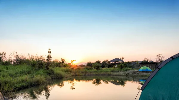 Barraca de acampamento ao lado da lagoa ao pôr do sol — Fotografia de Stock