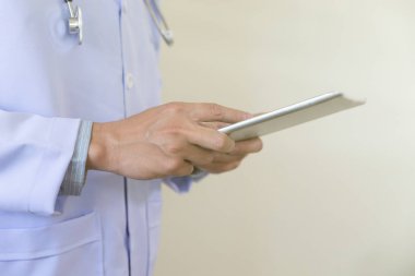 Beyaz önlüklü doktor iş yerinde tablet bilgisayarını kullanıyor.