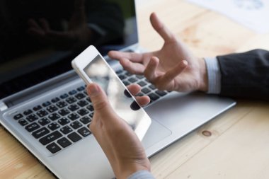 İşadamı ofiste akıllı telefon ve dizüstü bilgisayar kullanıyor.