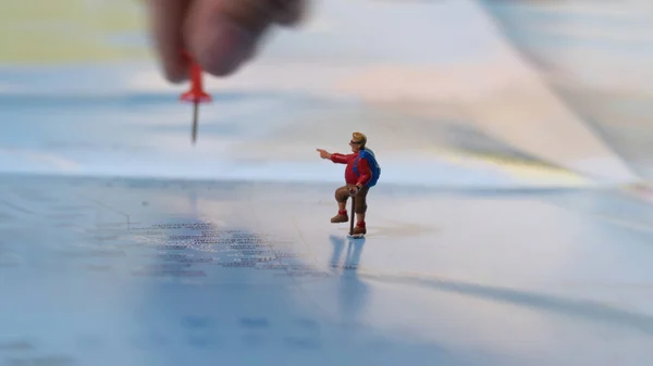 Mano colocando un alfiler rojo con viajero miniatura mini figura con — Foto de Stock