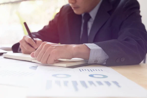 Empresário analisando gráficos e gráficos e tomando notas . — Fotografia de Stock