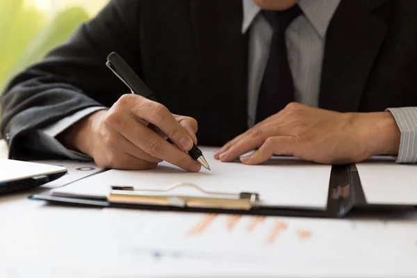 Empresario analizando gráficos y gráficos y tomando notas . — Foto de Stock