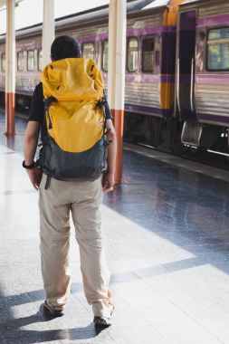 Trende sırt çantası ile istasyonu platformu üzerinde yürüyen genç adam