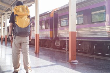 Trende sırt çantası ile istasyonu platformu üzerinde yürüyen genç adam