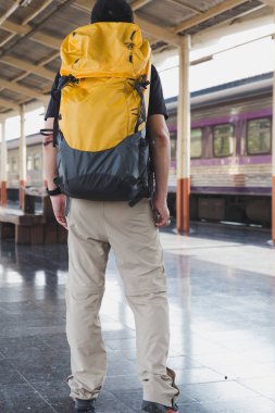 Trende sırt çantası ile istasyonu platformu üzerinde yürüyen genç adam