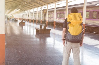 Trende sırt çantası ile istasyonu platformu üzerinde yürüyen genç adam