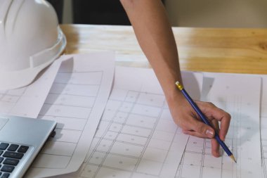 Ofisteki planlar ve dizüstü bilgisayarlarla çalışan mimar veya mühendis