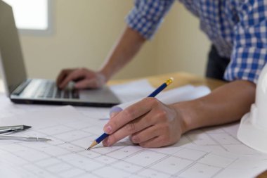 Ofisteki planlar ve dizüstü bilgisayarlarla çalışan mimar veya mühendis