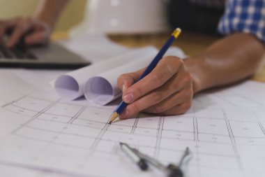 Ofisteki planlar ve dizüstü bilgisayarlarla çalışan mimar veya mühendis