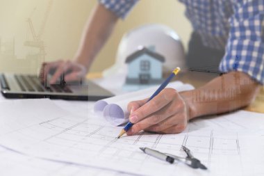 Ofisteki planlar ve dizüstü bilgisayarlarla çalışan mimar veya mühendis