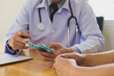 Doktor doktor kadın hastaya ilaç yazıyor.