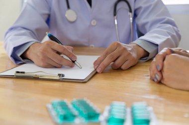 Doktor doktor kadın hastaya ilaç yazıyor.