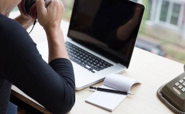 ahşap otururken kulaklık dizüstü bilgisayar ile tutarak Başlangıç adam