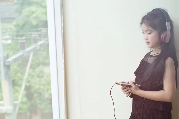 Bonita chica asiática sosteniendo el teléfono inteligente y escuchando música ingenio —  Fotos de Stock