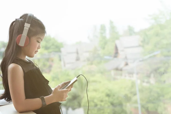 Menina asiática bonita segurando telefone inteligente e ouvindo música sagacidade — Fotografia de Stock