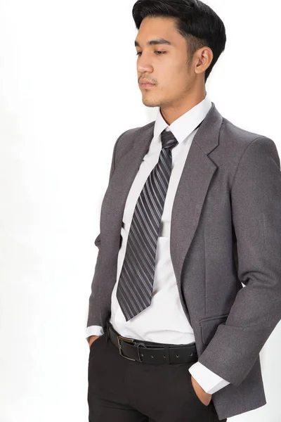 Бизнесмен в сером костюме стоит и позирует над белым Bac — стоковое фото