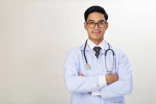 Lachende jonge mannelijke arts met de stethoscoop en gekruiste armen — Stockfoto