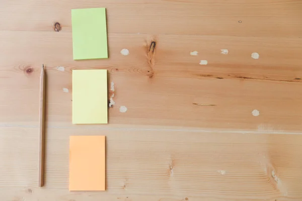 Плоский прошарок офісних приладдя - барвисті липкі ноти на дерев'яному бо — стокове фото