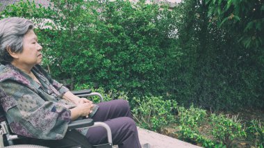 Yaşlı kadın tek başına dışarı bahçedeki tekerlekli sandalyede oturmak.