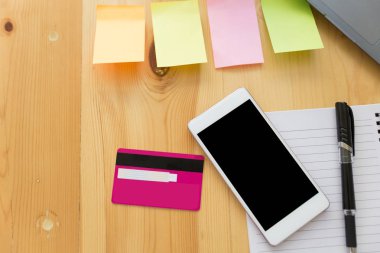 Akıllı telefonlu ahşap ofis masası, kredi kartı, defter, yapışkan