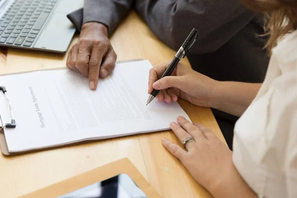 La mano de la persona sostiene la escritura del bolígrafo en el papel del acuerdo ella — Foto de Stock