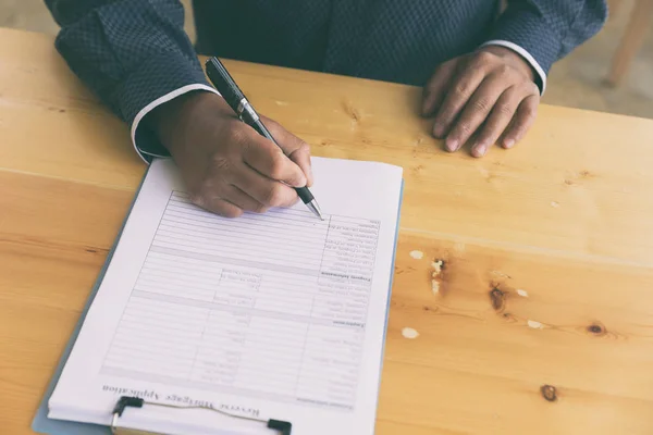 Llenar a mano la solicitud de préstamo hipotecario inverso en un portapapeles . — Foto de Stock